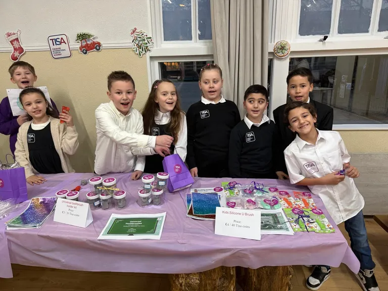 TISA students selling their products at the school market stall under the TISA sign