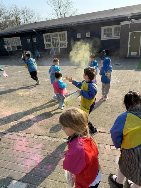 Students throwing colorful powder in the schoolyard during a Holi-style celebration